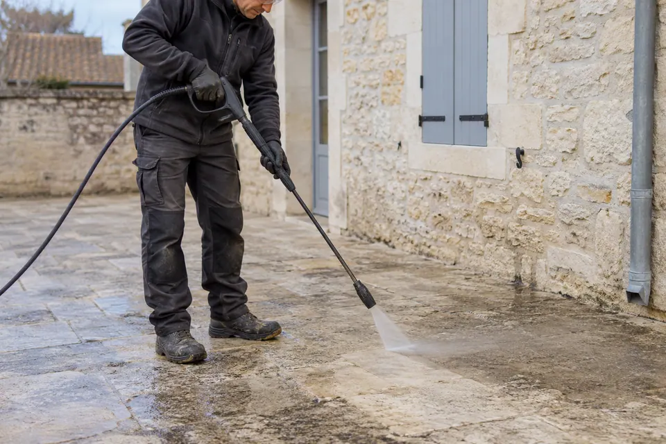 Artisan nettoyant le dallage d’une cour — illustration générée